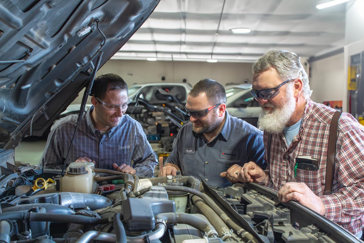 Collegues working together over the engine bay of a work truck.